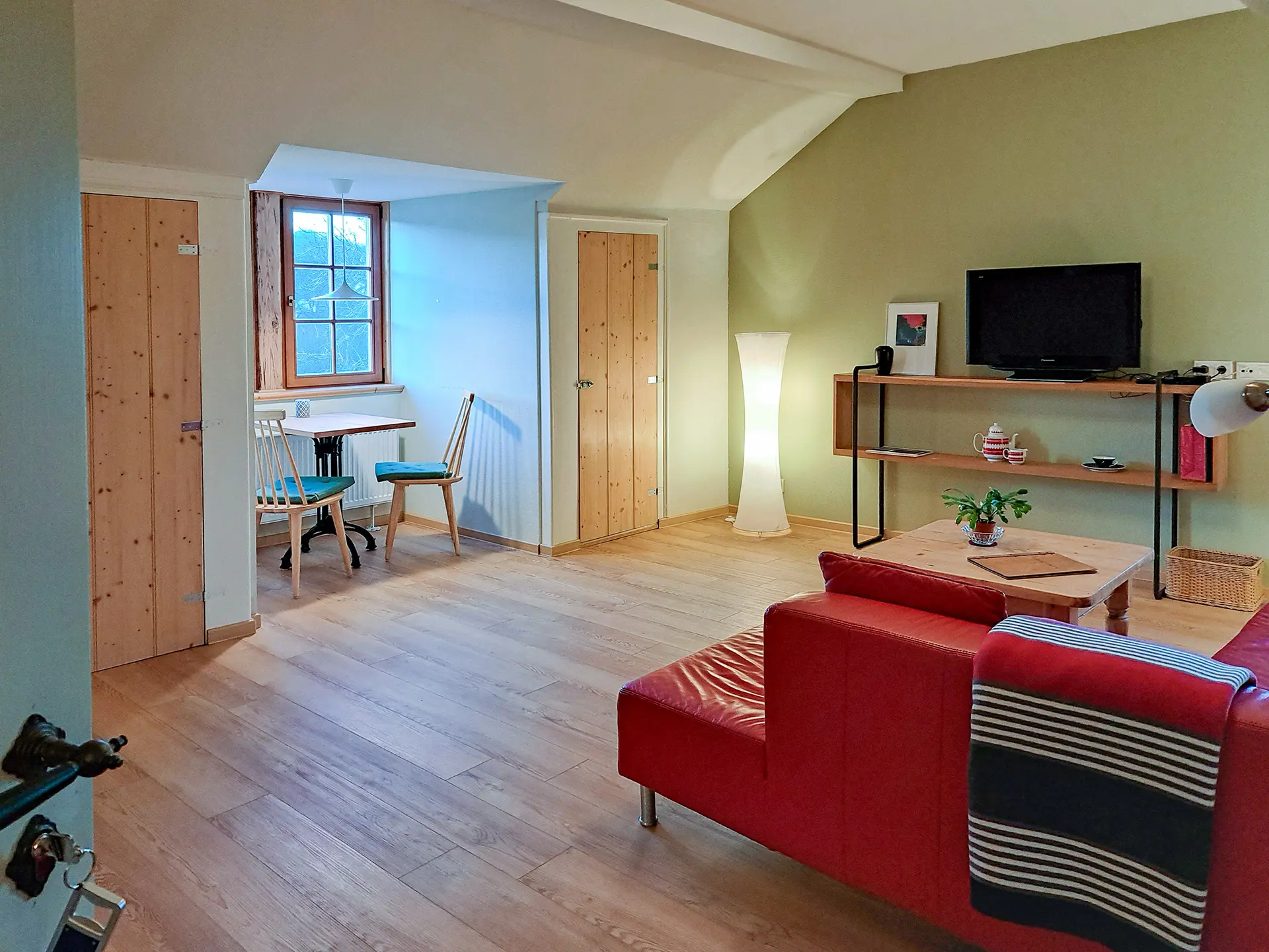 Gemütlicher Wohnbereich der Ferienwohnung von Geyso im Schloß Roßdorf mit rotem Sofa, Essplatz und heller Einrichtung