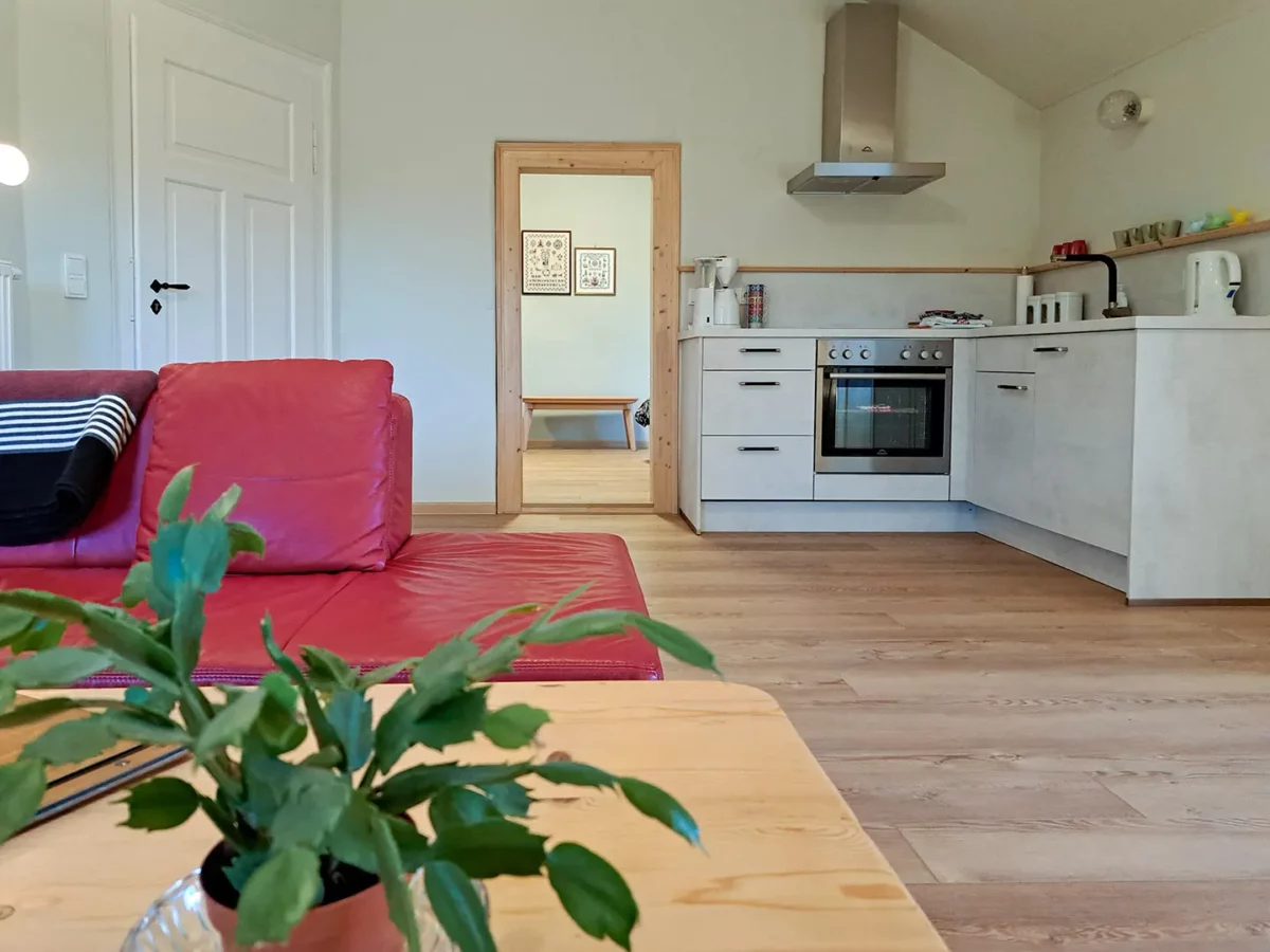 Wohnküche der Ferienwohnung von Geyso im Schloß Roßdorf mit rotem Sofa, offener Küchenzeile und hellem Wohnbereich