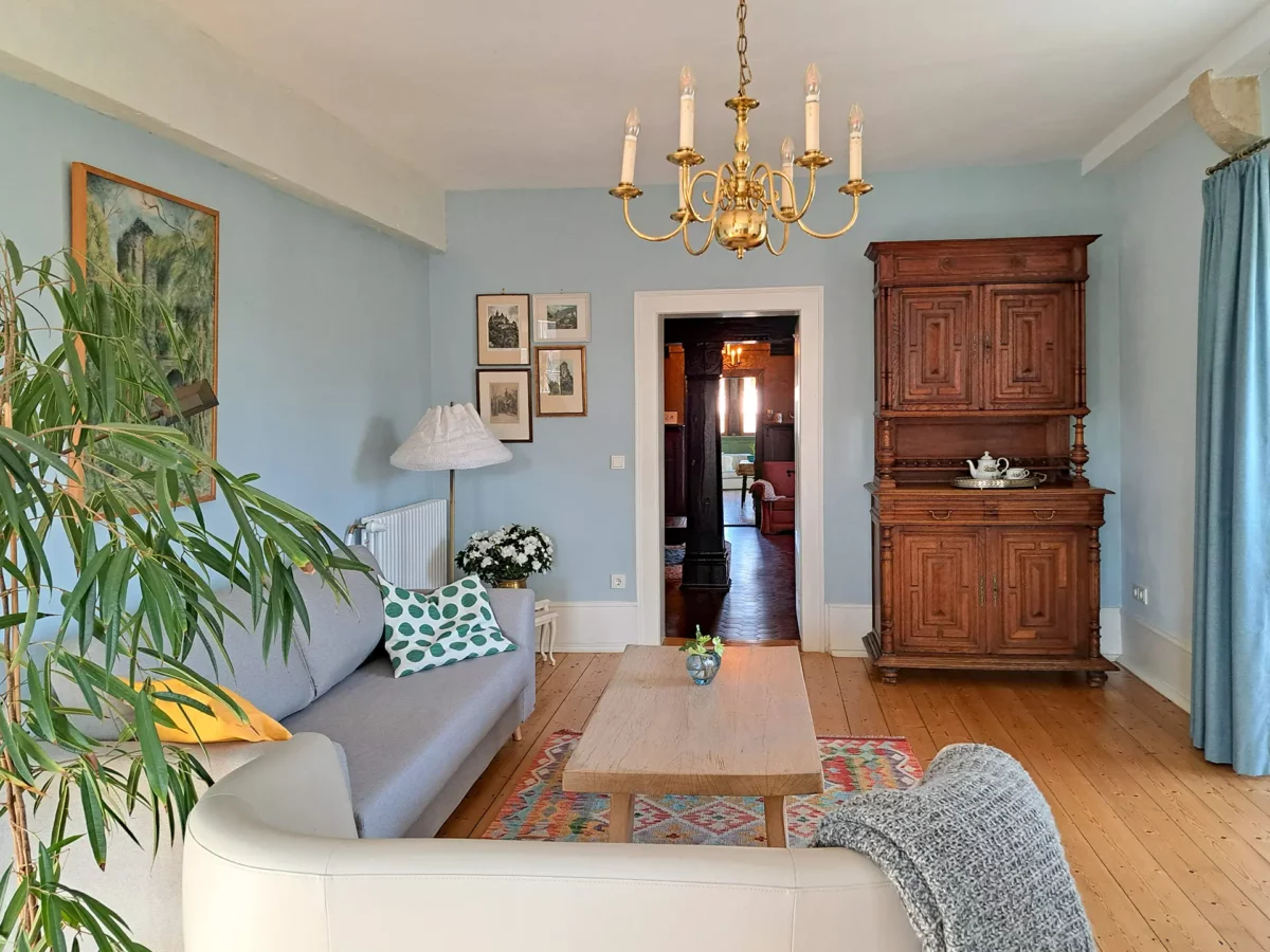 Stilvolles Wohnzimmer der Ferienwohnung von Henneberg im Schloß Roßdorf mit Sofa, historischem Schrank, Holzboden und gemütlicher Einrichtung