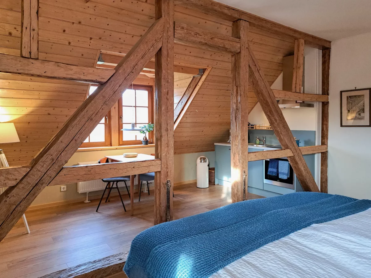 Schlafbereich der Ferienwohnung von Eschwege im Schloß Roßdorf mit historischem Fachwerk, Bett, Esstisch und Küchenzeile