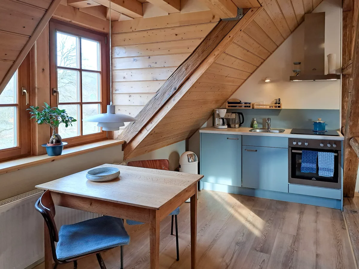 Essbereich und Küche der Ferienwohnung von Eschwege im Schloß Roßdorf mit Holzbalken, Esstisch und moderner Küchenzeile