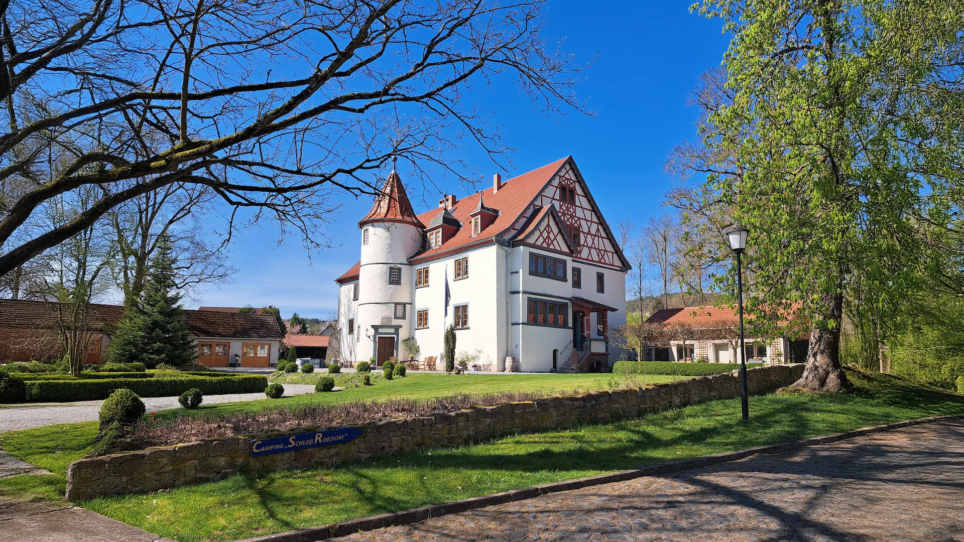 Straßenansicht von Schloß Roßdorf mit historischem Gebäude, Grünanlage und Zufahrt zum Campingplatz in Roßdorf